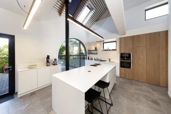 Moderne keuken met wit eiland witte lage kasten en eiken kolomkasten greeploos zwarte railverlichting