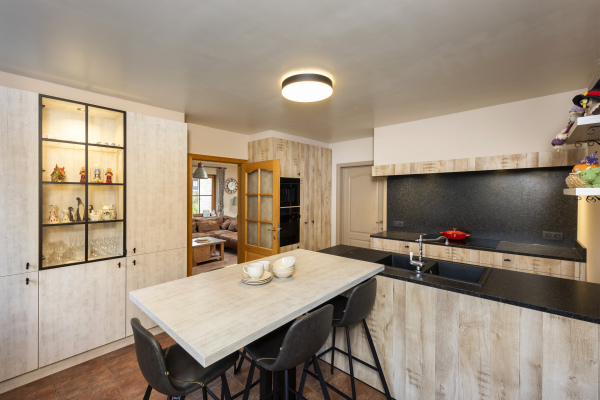 Landelijke keuken met stalen deur lichte houten fronten en zwarte knopgreepjes